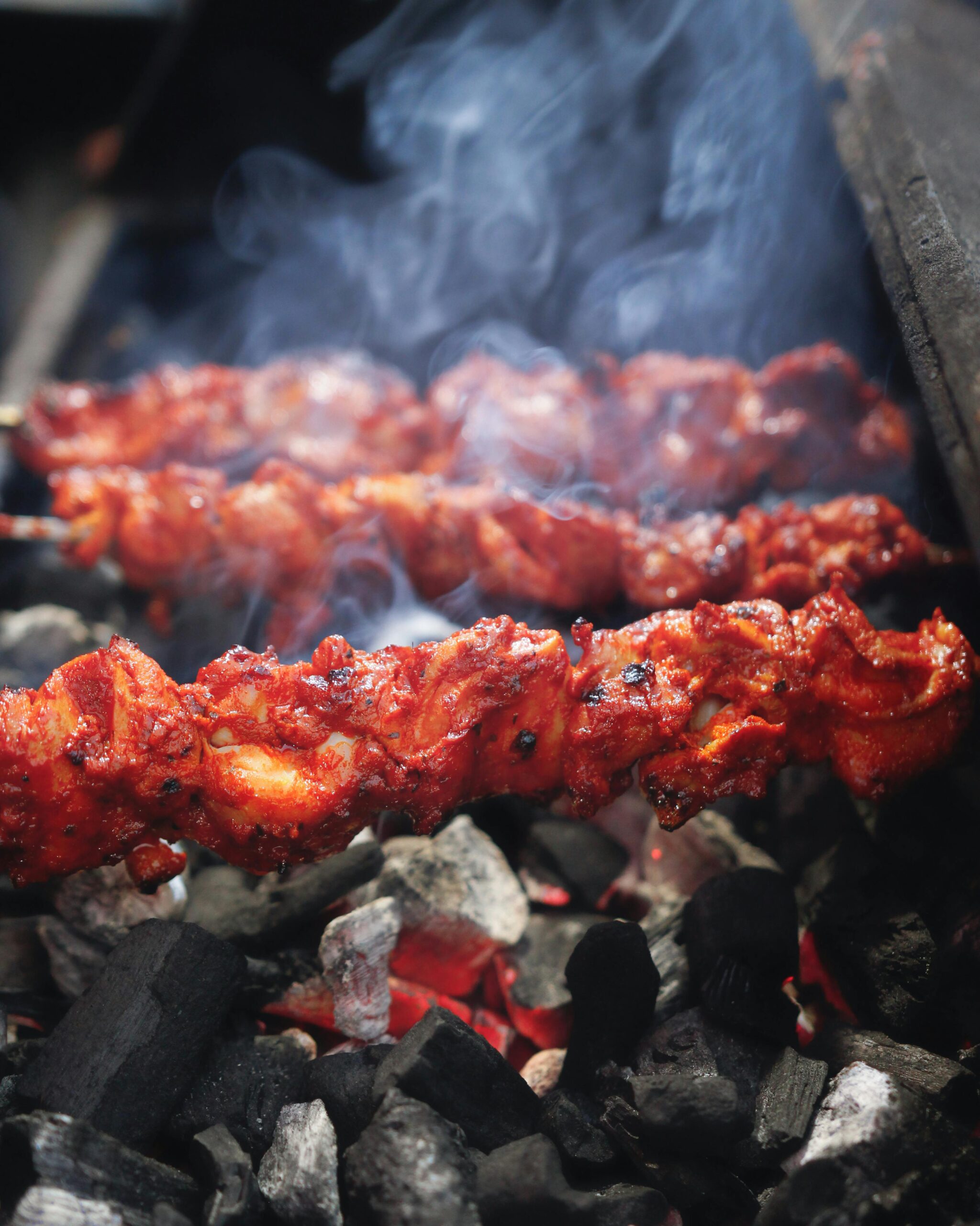 Close-up of sizzling grilled skewers on a charcoal BBQ, capturing the smoky aroma and delicious texture.